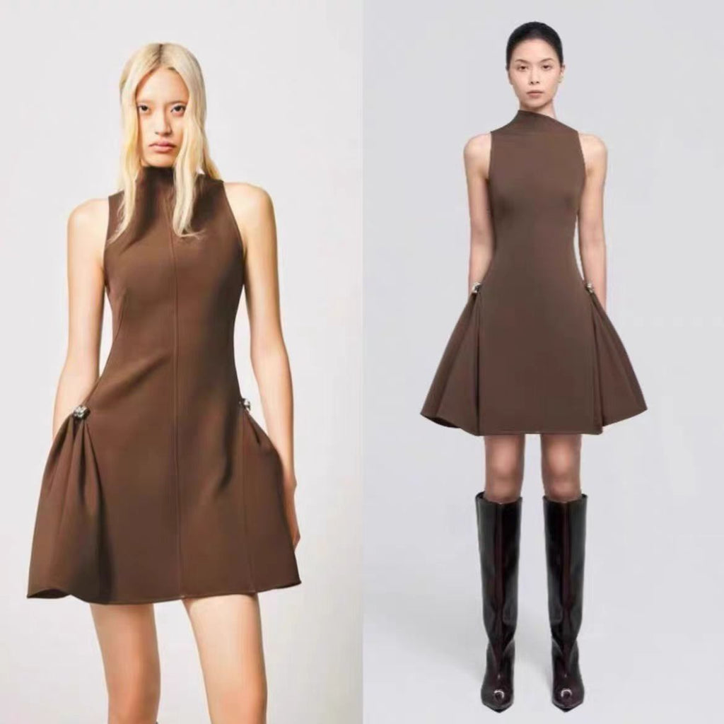 A short, sleeveless dress featuring symmetrical pleats, a metal buckle, and a waist accent.