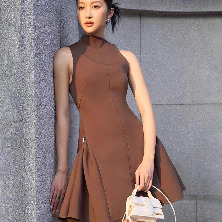 A short, sleeveless dress featuring symmetrical pleats, a metal buckle, and a waist accent.